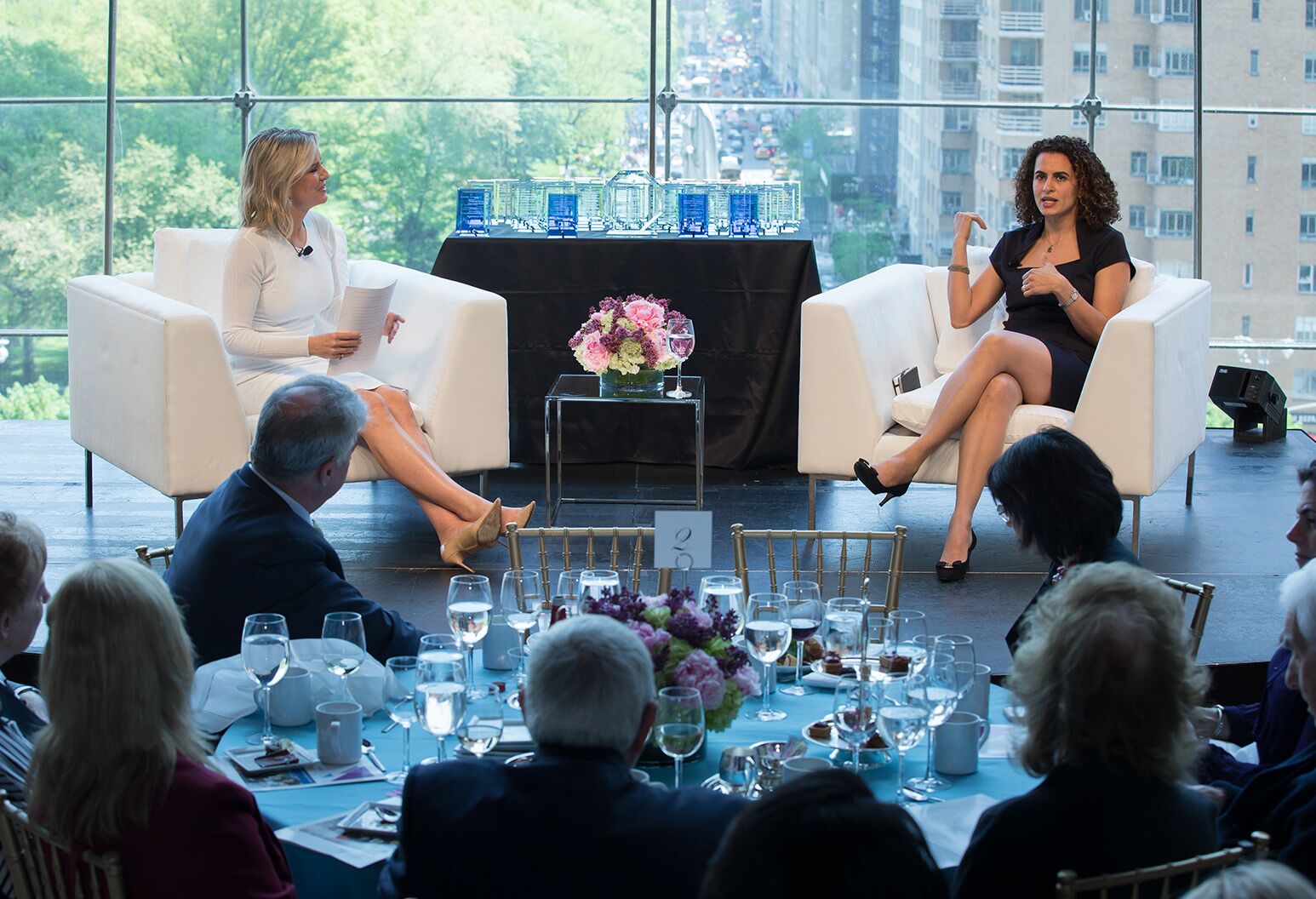 Two women speaking at a conference in front of an audience. 